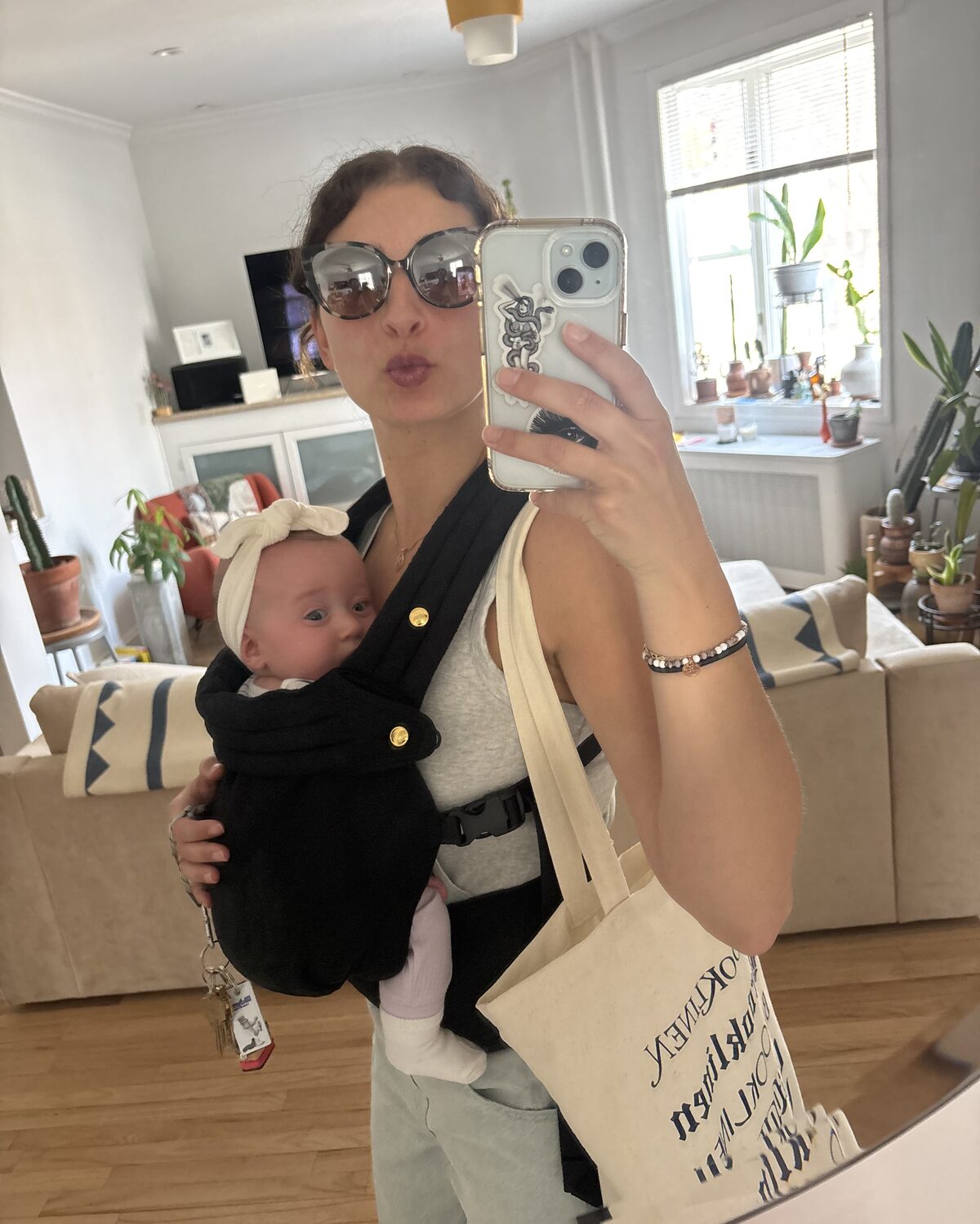 A mum carrying her baby in a soft carrier at home